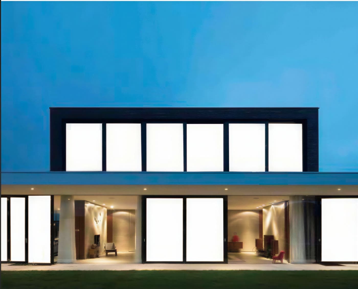 Moderne villa ved skumring med smart glass-partier i mat tilstand